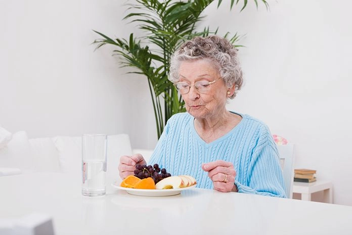 Dame âgée qui prend un repas