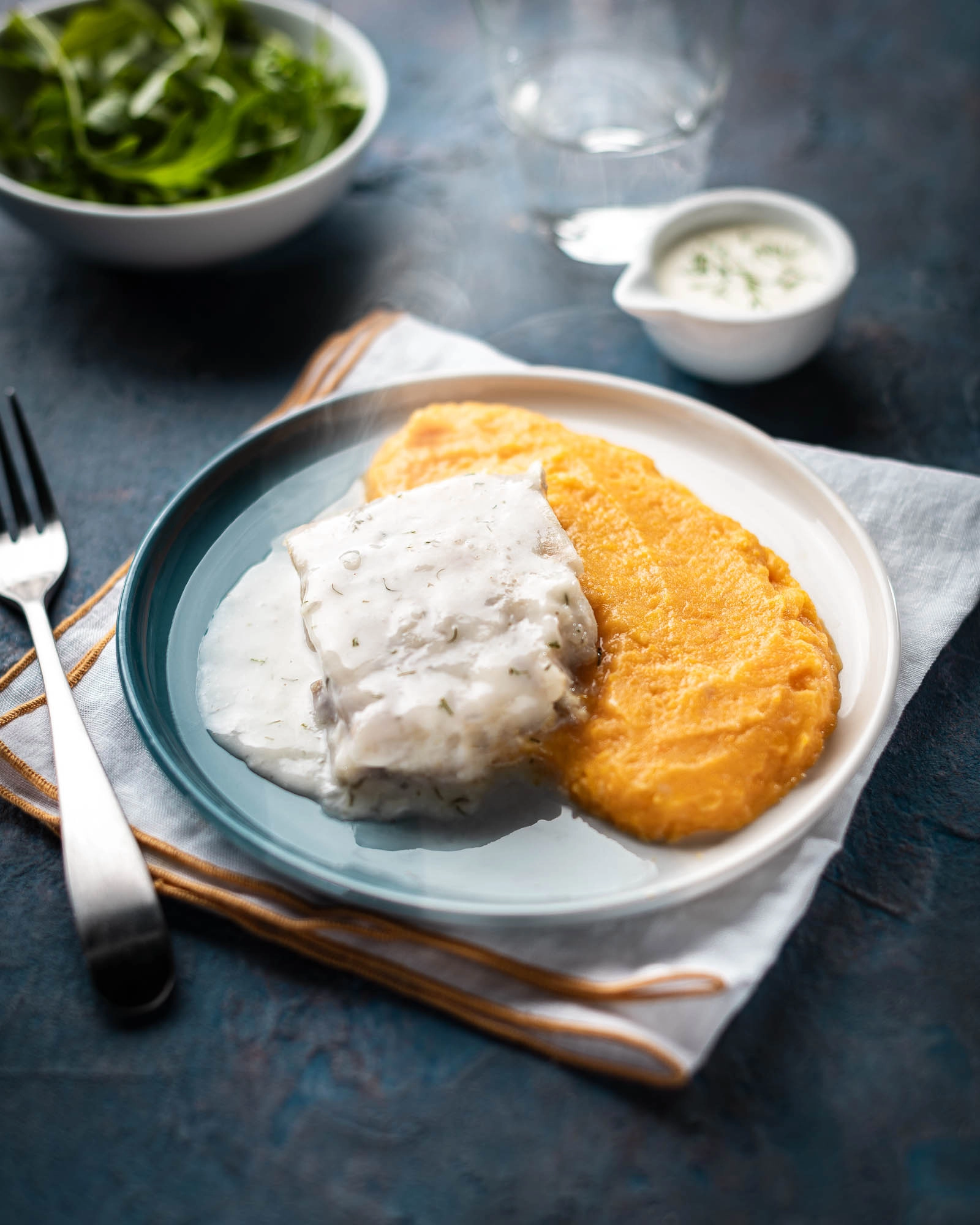 Assiette contenant un Pavé de lieu à l’aneth et une purée de courges dressé sur une table